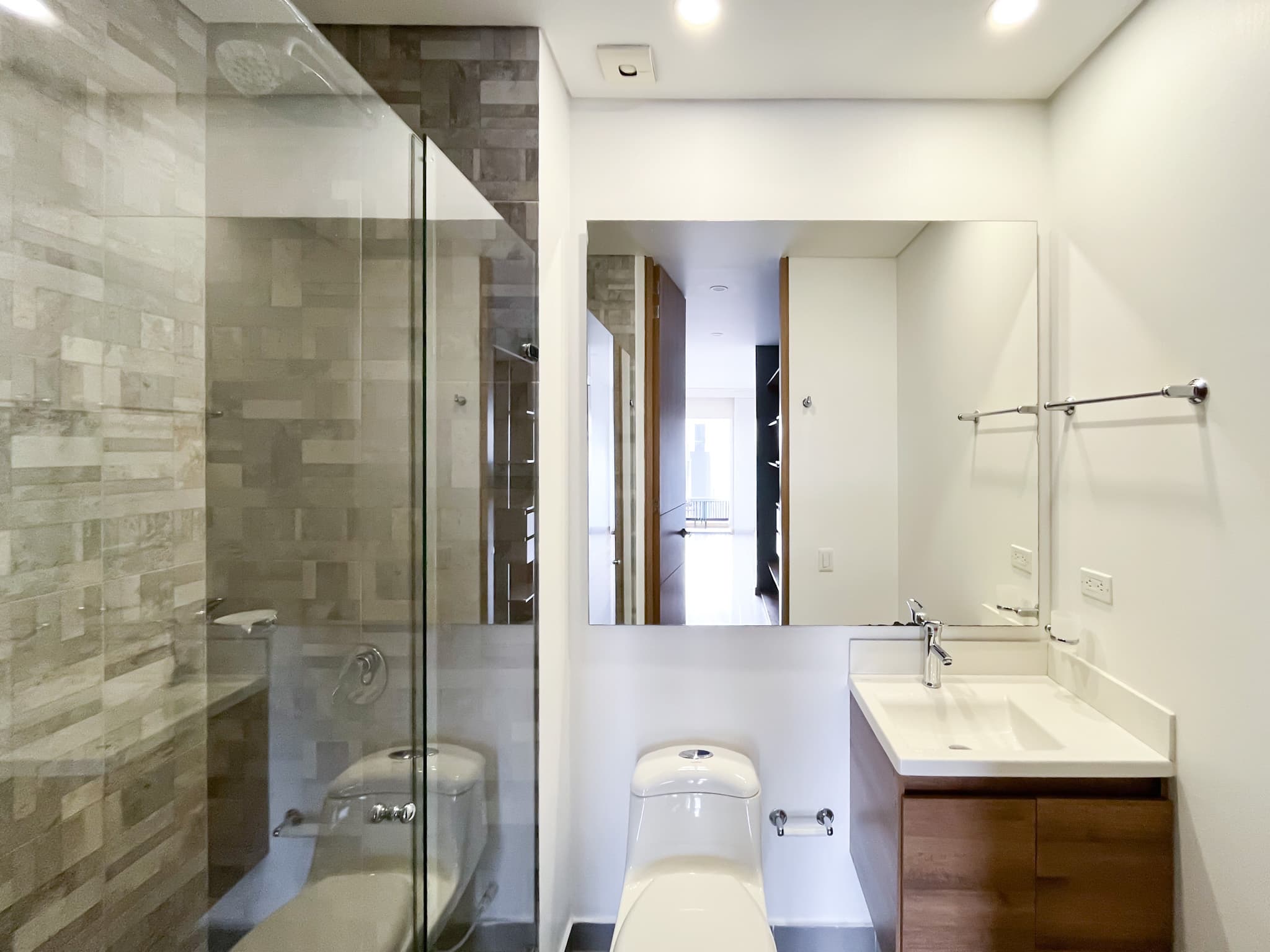 Baño completo con ducha en vidrio y enchape en piedra