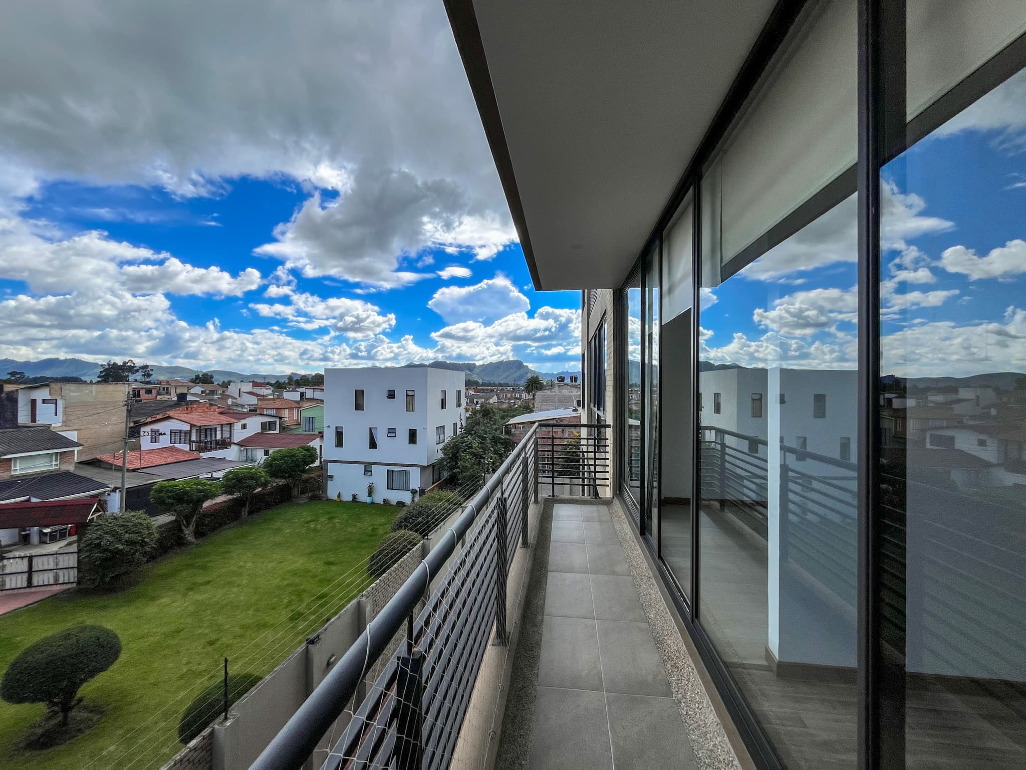 Balcón con vista a la sabana, jardines y cerros bajo cielo despejado