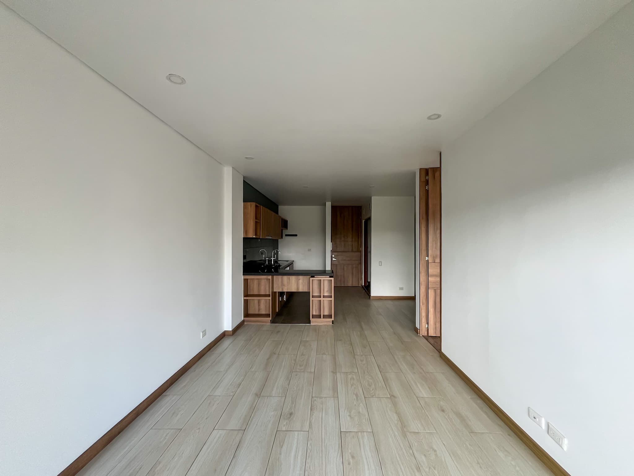 Sala abierta con piso en cerámica y cocina integrada en granito y aglomerado laminado MDP
